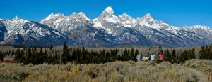 Teton mountain range panorama with three tourists looking at scene
